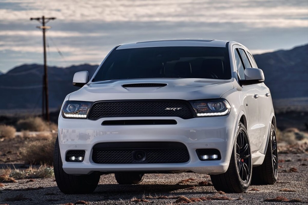 A white 2018 Dodge Durango SRT sits in the sunlight with its lights on.