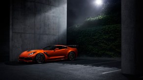 A bright-orange Corvette parks in a garage under the moon.