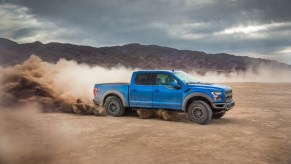 The 2020 Ford F-150 in blue driving on a dusty road. This 2020 used truck offers great value