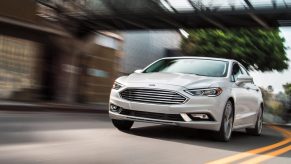 A white 2020 Ford Fusion drives down a city street.
