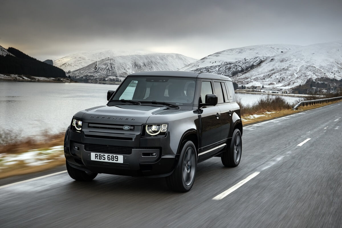 A dark-gray 2022 Land Rover Defender 110 V8 drives through a country road.