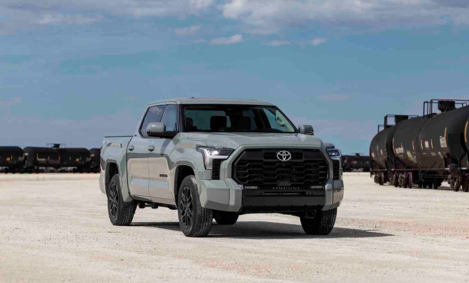 Gray Toyota Tundra pickup truck parked on a dirt lot, a locomotive in the background.