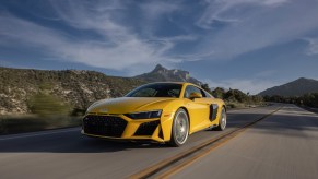 Bright yellow 2023 Audi R8 one of the cheapest supercars you can buy new in 2023 driving on road front 3/4