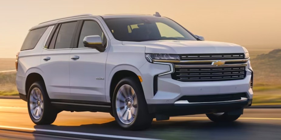 A white 2023 Chevrolet Tahoe full-size SUV is driving on the road. 
