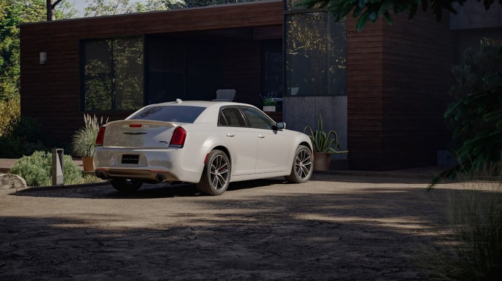 A white 2023 Chrysler 300 sits on a driveway next to a modern home.