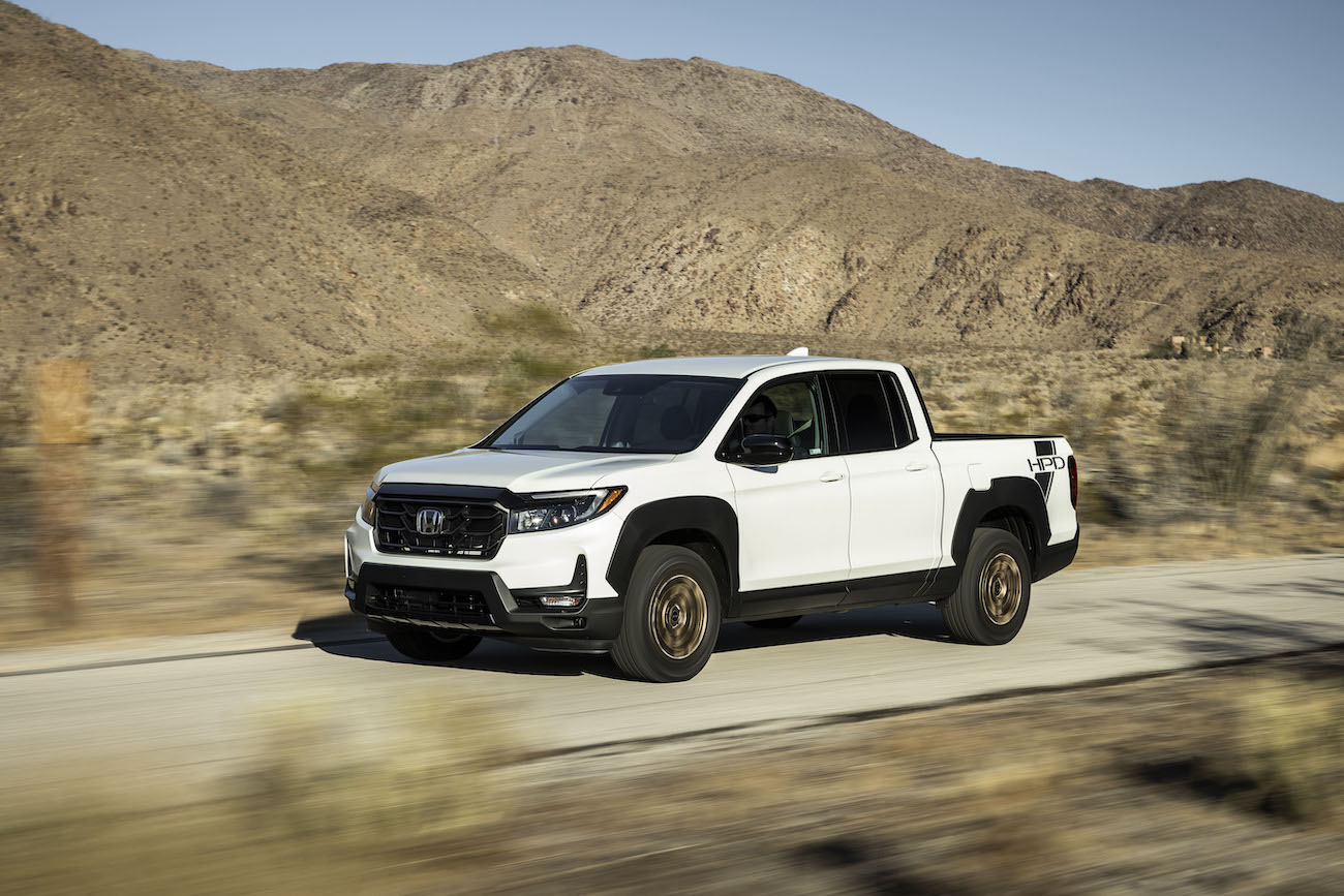 A white 2023 Honda Ridgeline driving in the desert. Honda Ridgeline sales should be higher than what they are.