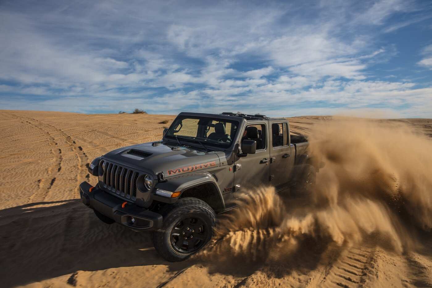 A 2023 Jeep Gladiator driving in some sand.
