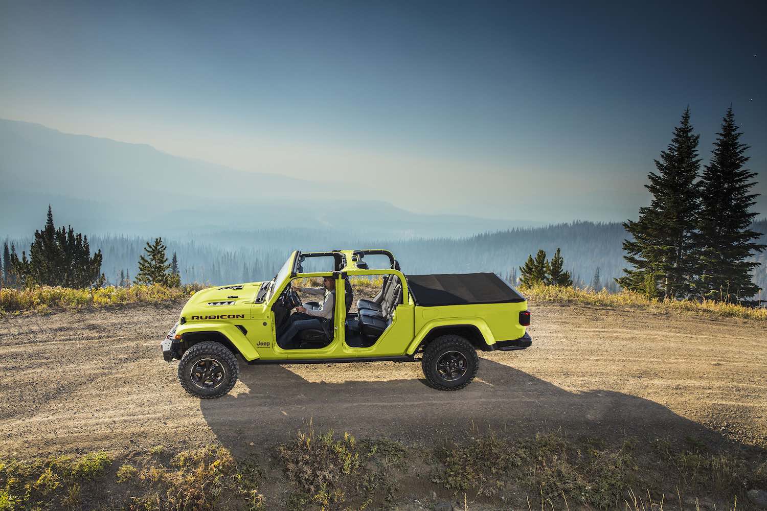 2023 Jeep Gladiator pickup truck parked on a mountain road with its top down.