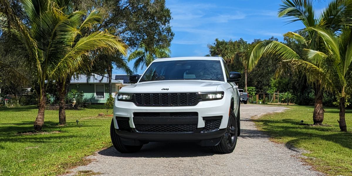 A white 2023 Jeep Grand Cherokee L midsize three-row SUV is parked in a driveway.