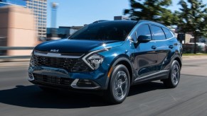 A bleu 2023 Kia Sportage Hybrid small hybrid SUV is driving on the road.