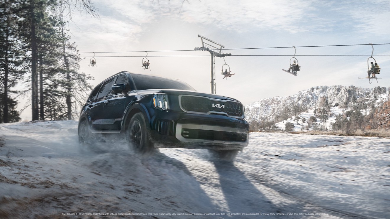 A blue 2023 Kia Telluride on a snowy hill with a ski lift in the background. The Telluride vs. Atlas debate is alive and well.