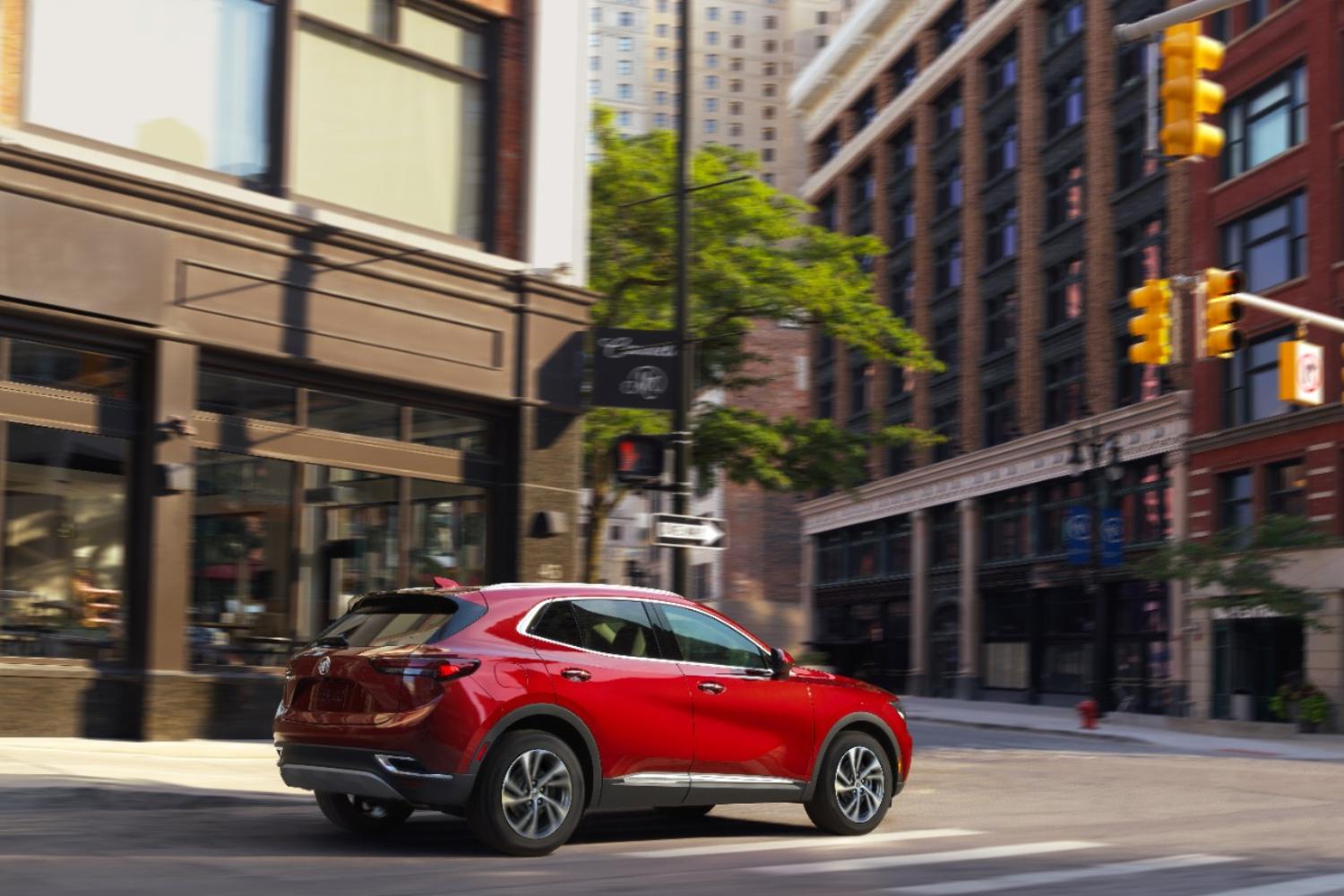 A red 2023 Buick Envision driving down a city street.