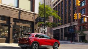A red 2023 Buick Envision driving down a city street.