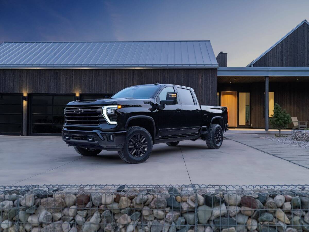 A 2024 Chevy Silverado HD High Country heavy-duty pickup truck model parked outside a home shed on concrete