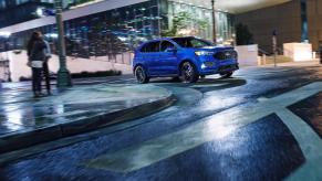 A blue Ford Edge driving in the city at night. 2024 Ford Edge trims are already seeing some be more popular than others