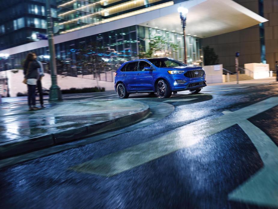 A blue Ford Edge driving in the city at night. 2024 Ford Edge trims are already seeing some be more popular than others