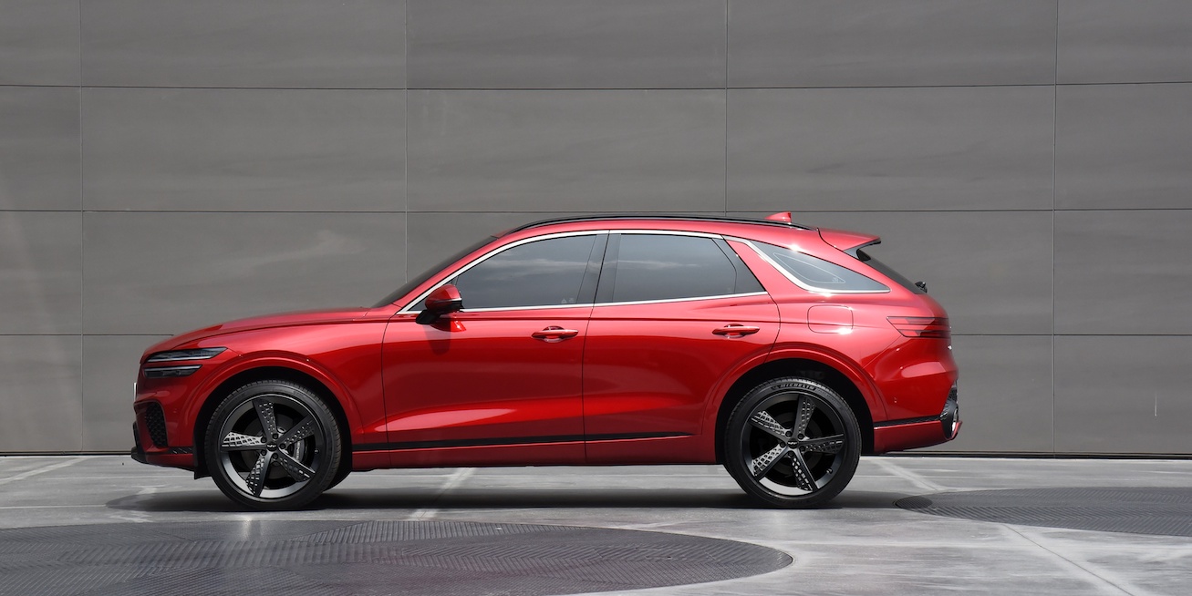 A red 2024 Genesis GV70 side view against a gray backdrop. 2024 Genesis GV70 trims come in only two configurations.