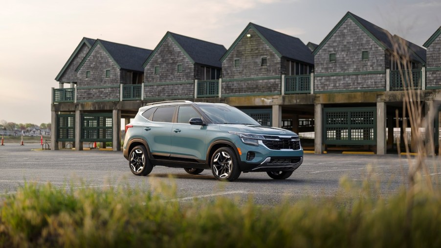 A 2024 Kia Seltos in Photon Blue near the beach and some elevated buildings. The 2024 Kia Seltos' price is an attractive point.