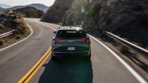 The rear of a gray 2024 Kia Sportage driving a long a winding road. The 2024 Kia Sportage's price is a big positive point for the SUV.