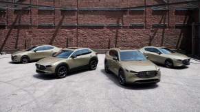 2024 Mazda3 sedan, CX-30, CX-5, and Mazda3 hatchback Carbon Turbo editions lined up in front of a red-brick building