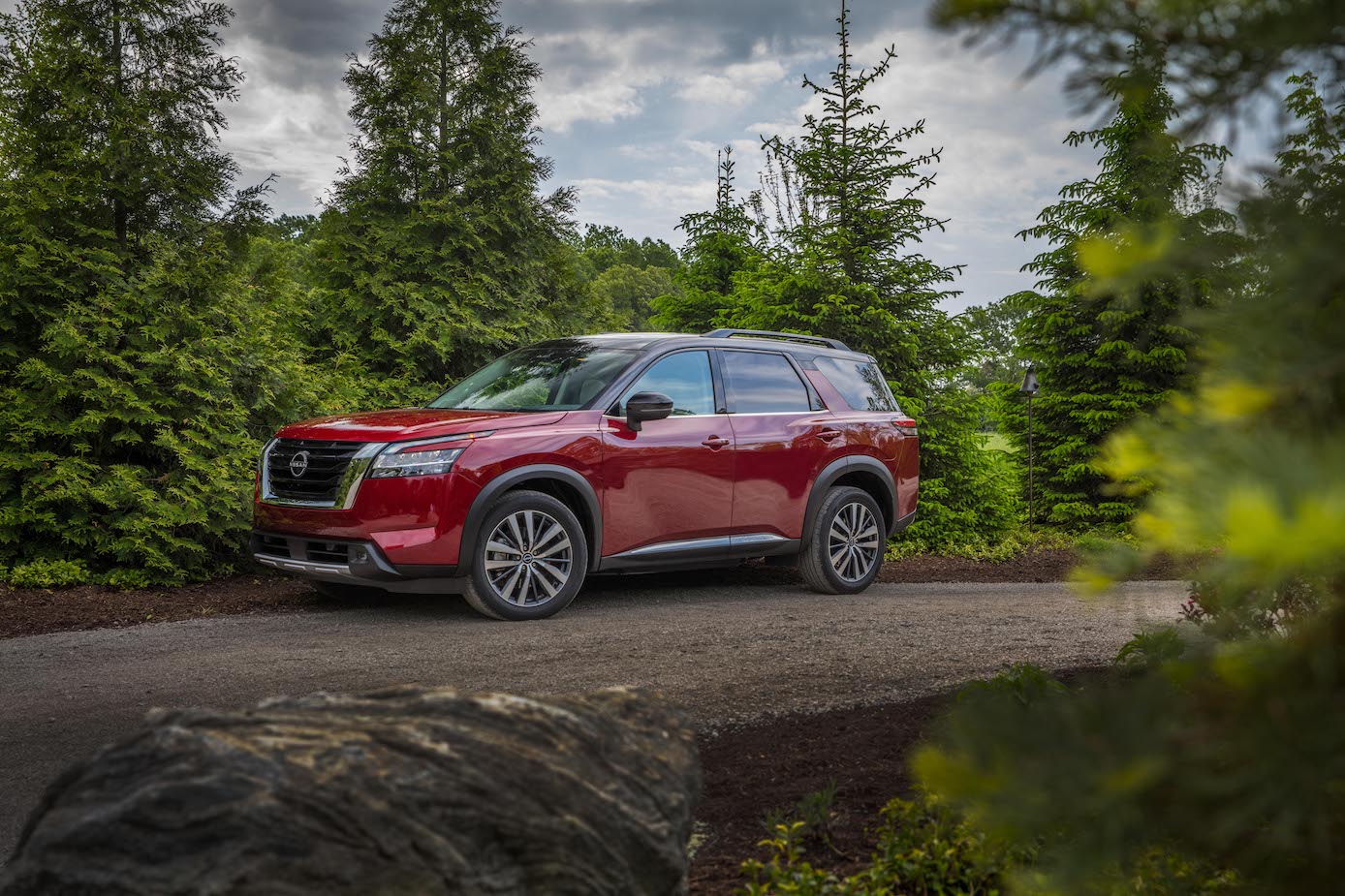 A red 2024 Nissan Pathfinder in the woods. The 2024 Nissan Pathfinder trims have one that stand out more than the rest