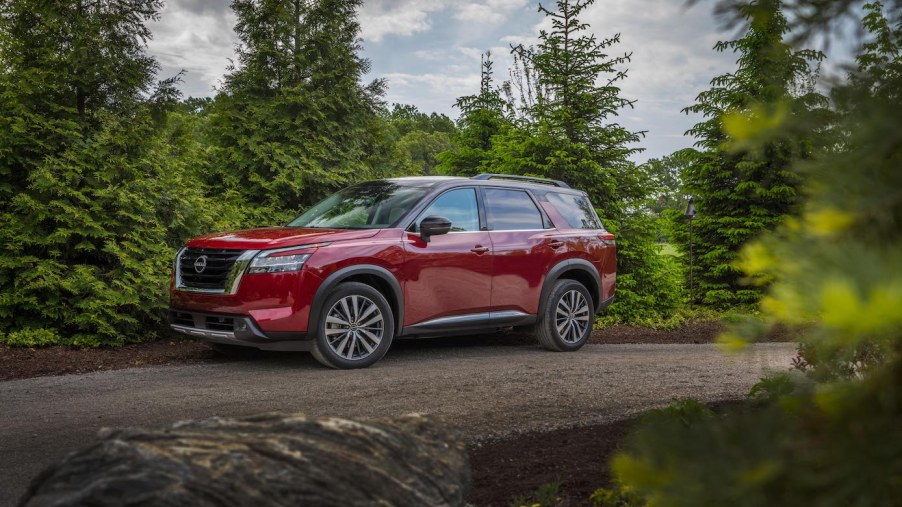 A red 2024 Nissan Pathfinder in the woods. The 2024 Nissan Pathfinder trims have one that stand out more than the rest