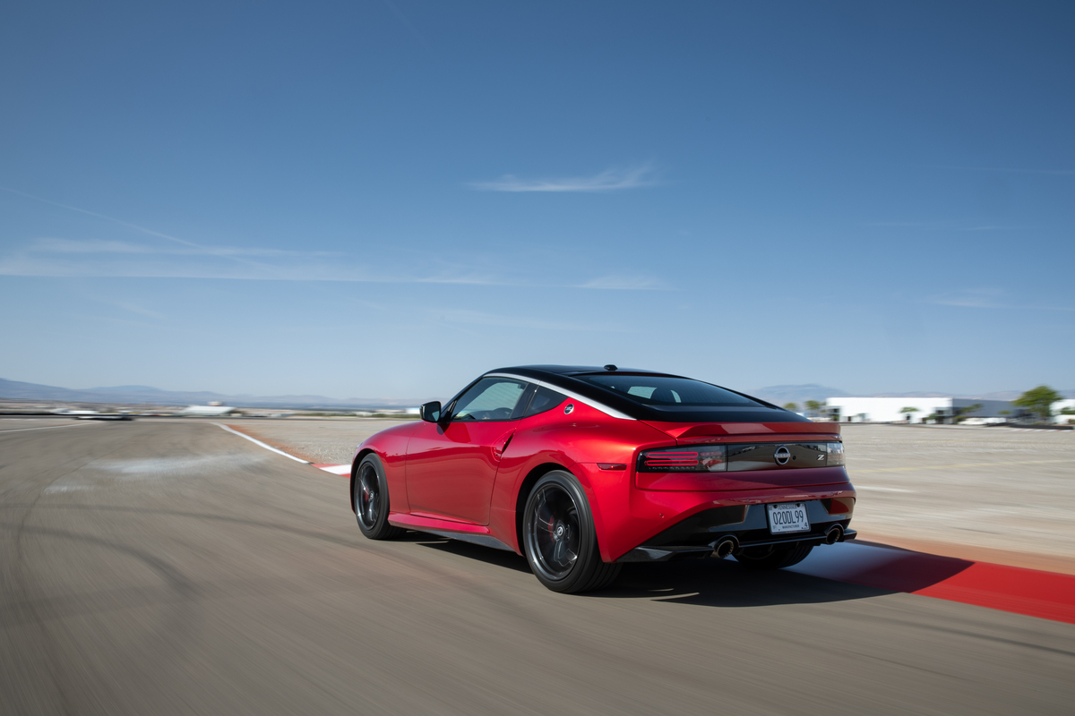 Rear view of a red 2024 nissan z driving on a race track