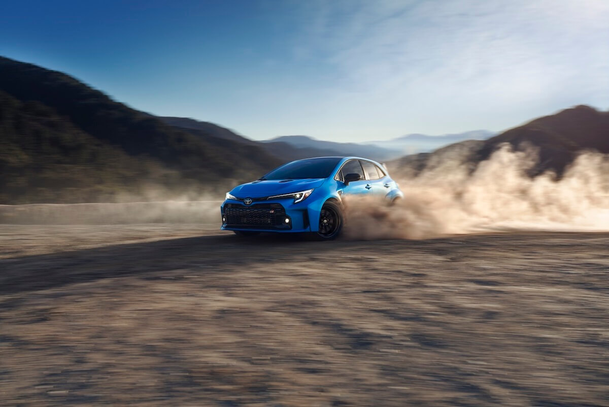 A blue 2024 Toyota GR Corolla all-wheel drive sports car sliding through the desert.