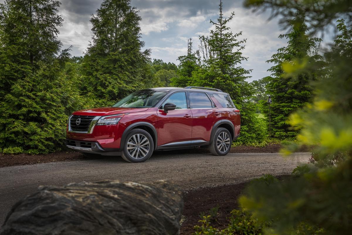 A red Nissan Pathfinder in the woods.