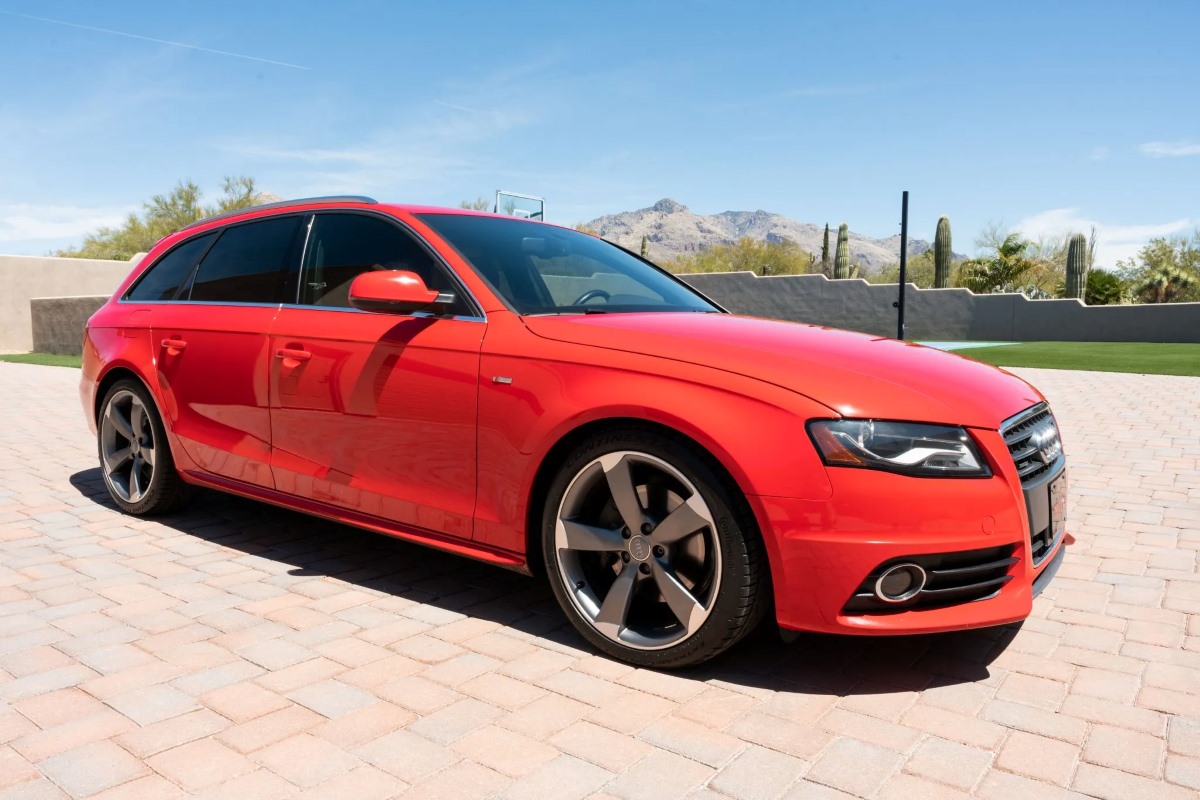 A red Audi A4 Avant parked outdoors on a paver driveway
