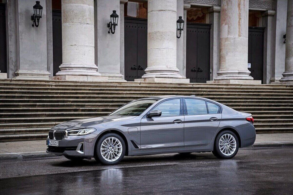 A gray BMW 5 Series luxury AWD car sits in wait outside of a government building.