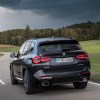 The rear of a black BMW X3 driving on a stormy road. The BMW X3's price isn't that bad compared to others in the class.