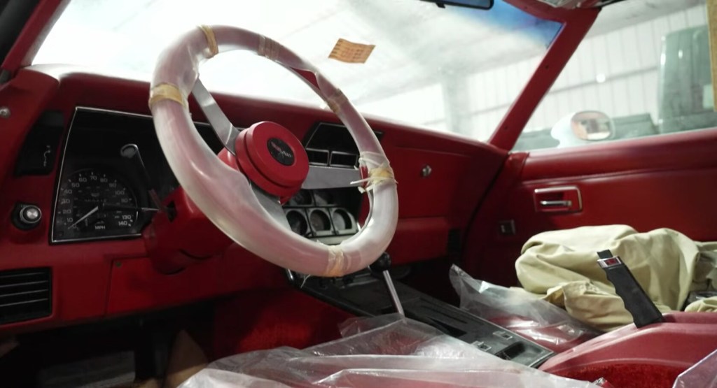 The interior of a brand-new vintage Corvette with all the plastic still covering the interior.