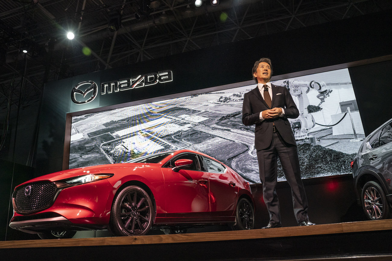 Masahiro Moro, CEO of Mazda Motor of America Inc., speaks while standing in front of a Mazda Motor Corp. 3 AWD sedan during the 2019 New York International Auto Show