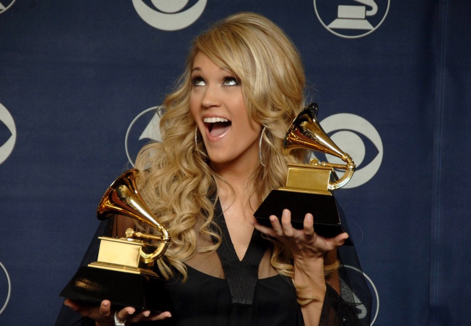Country singer Carrie Underwood standing on a stage holding a trophy.