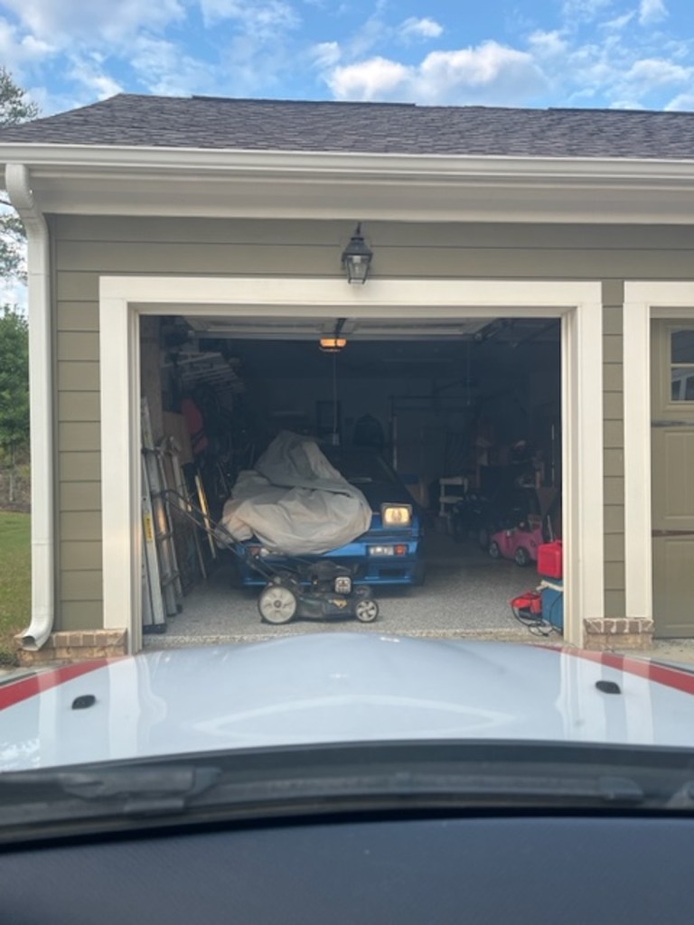 A 1988 Chrysler Conquest TSI sticking out of a garage