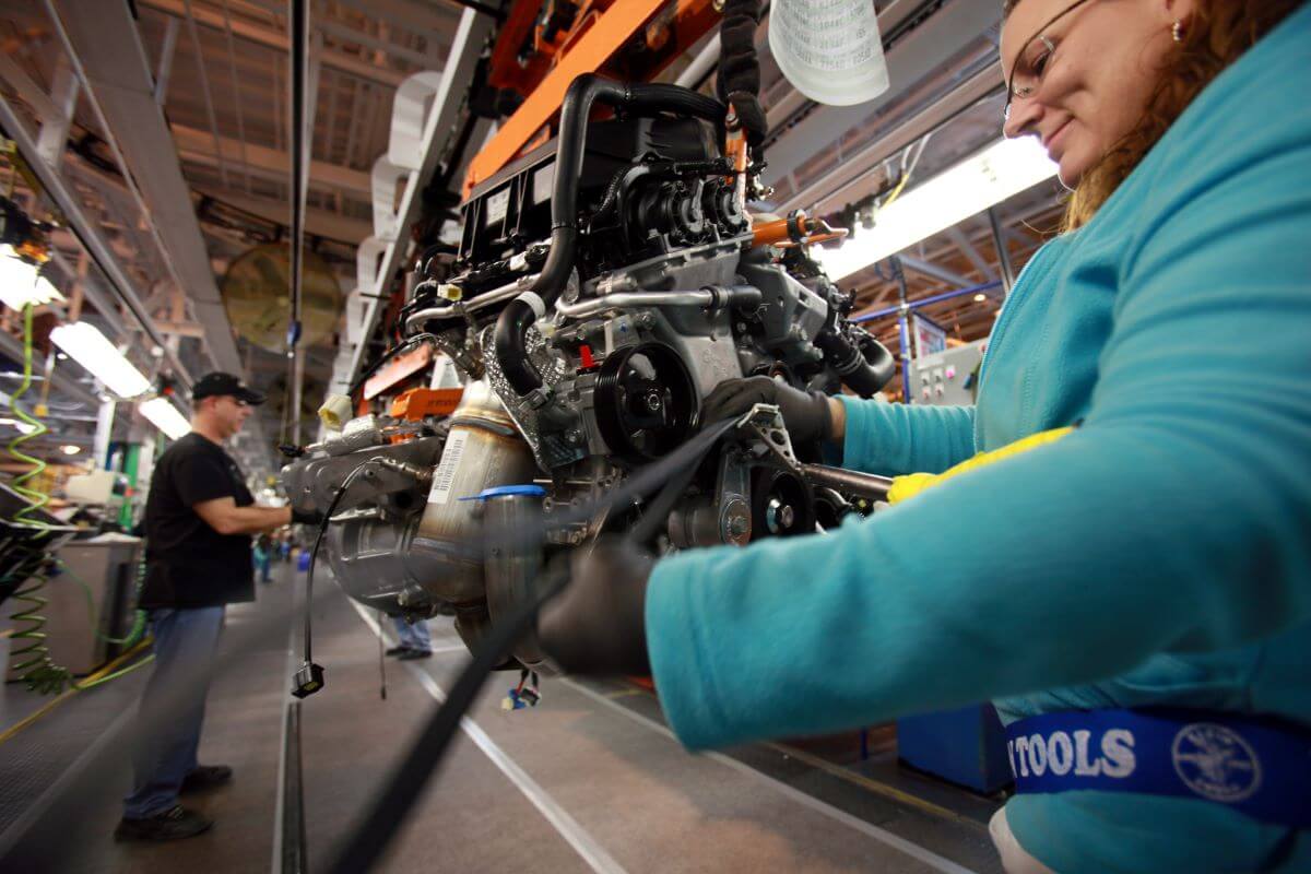 A worker installing a timing belt on a Chrysler minivan motor at the Windsor assembly plant in Ontario