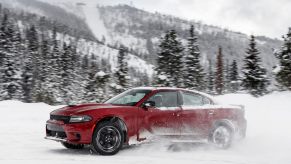 A Dodge Charger GT AWD sedan kicks up snow from the left side of the car.