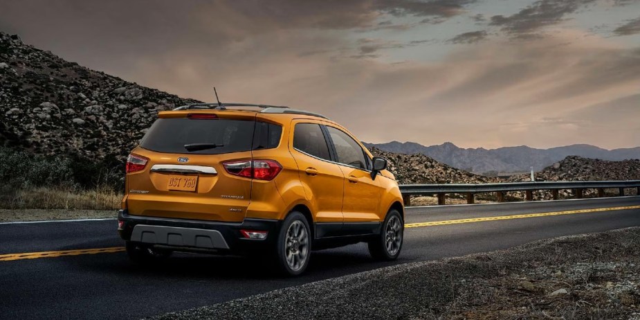 An orange Ford EcoSport subcompact SUV is driving on the road. 