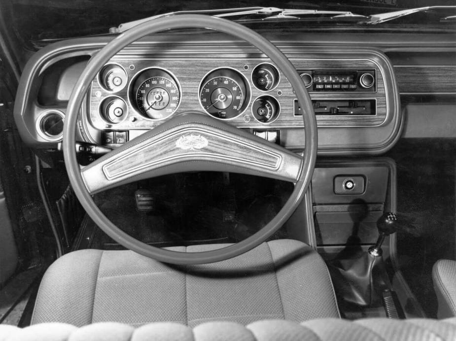 A black and white photo of a Ford Granada interior featuring its steering wheel, dashboard, and transmission