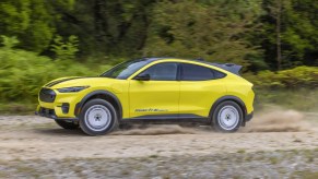A yellow 2024 Ford Mustang Mach-E Rally is driving on a trail.