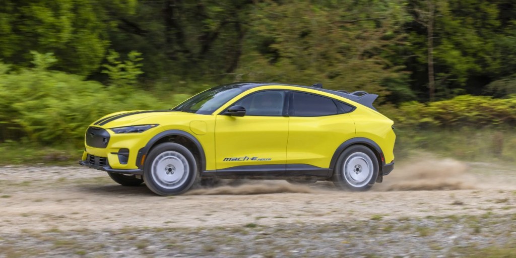A yellow 2024 Ford Mustang Mach-E Rally is driving on a trail.