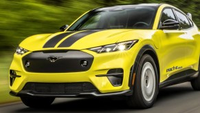 A yellow Ford Mustang Mach-E Rally small electric SUV is driving.