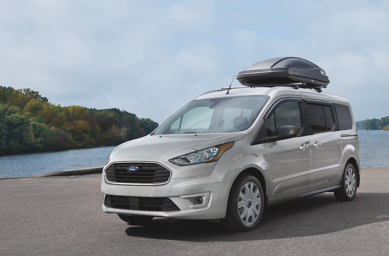 A silver Ford Transit Connect driving next to a lake. Ford Transit sales aren't doing too hot right now.