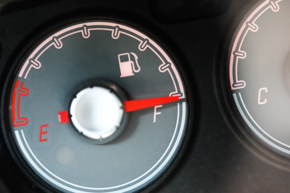 Black fuel gauge with a red needle pointing at a white "F" across from the letter "E"