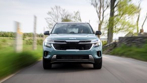 A 2024 Kia Seltos in Photon Blue speeding down a country road. This Kia SUV offers a ton of value