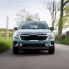 A 2024 Kia Seltos in Photon Blue speeding down a country road. This Kia SUV offers a ton of value