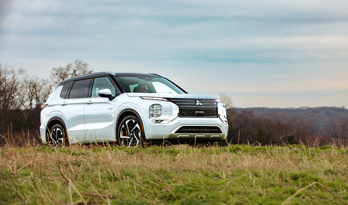 A white Mitsubishi Outlander parked in a open field. The Outlander is one of the safest SUVs in 2023.