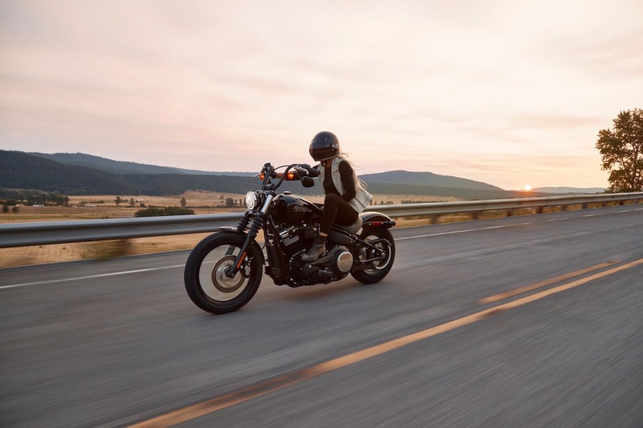 Woman rides a Harley-Davidson motorcycle through the mountains.