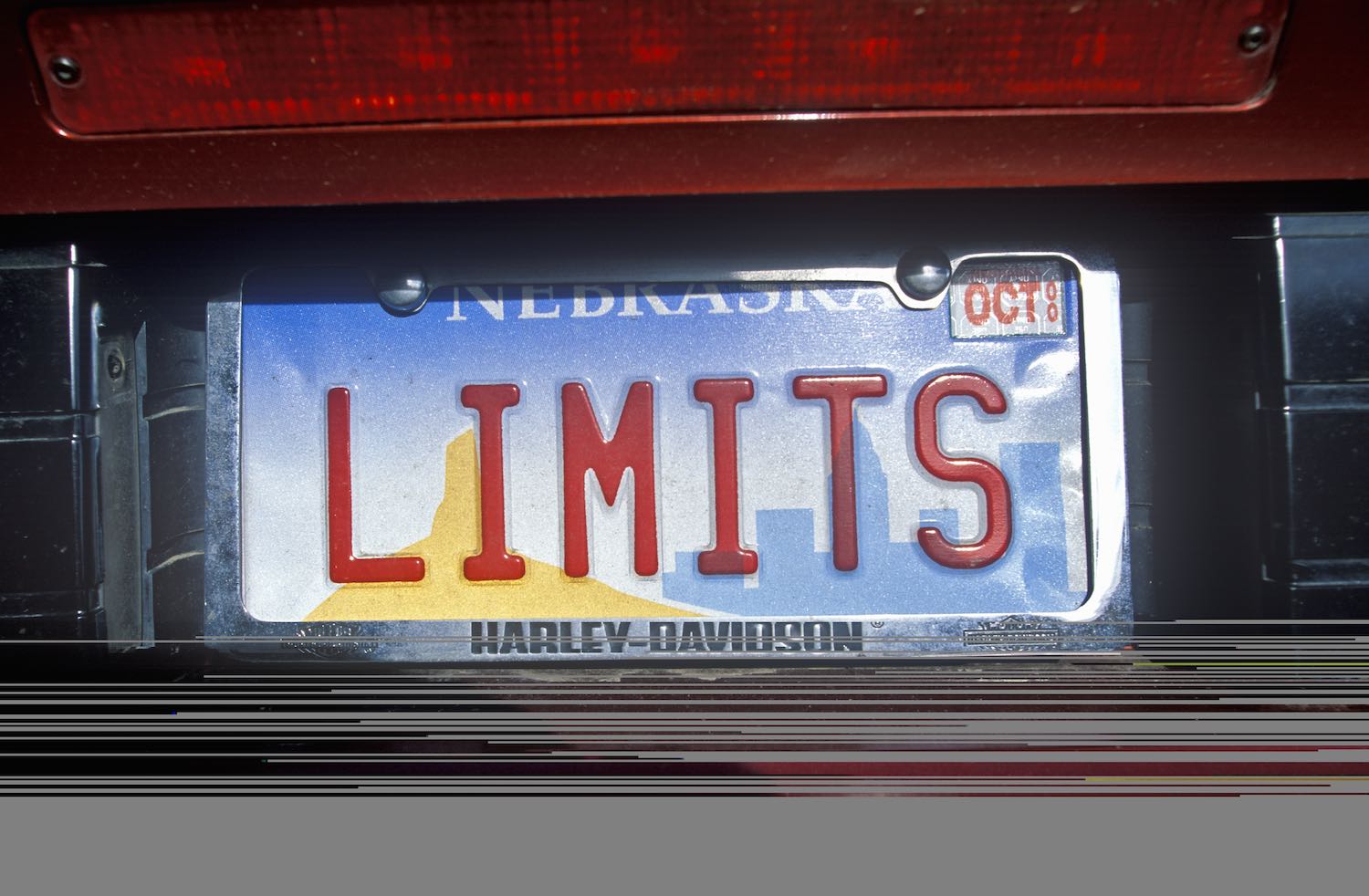 Nebraska Vanity license plate that says "Limits" on the back of a red car.